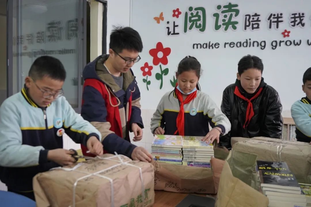 志愿者与孩子们一起整理分发的图书